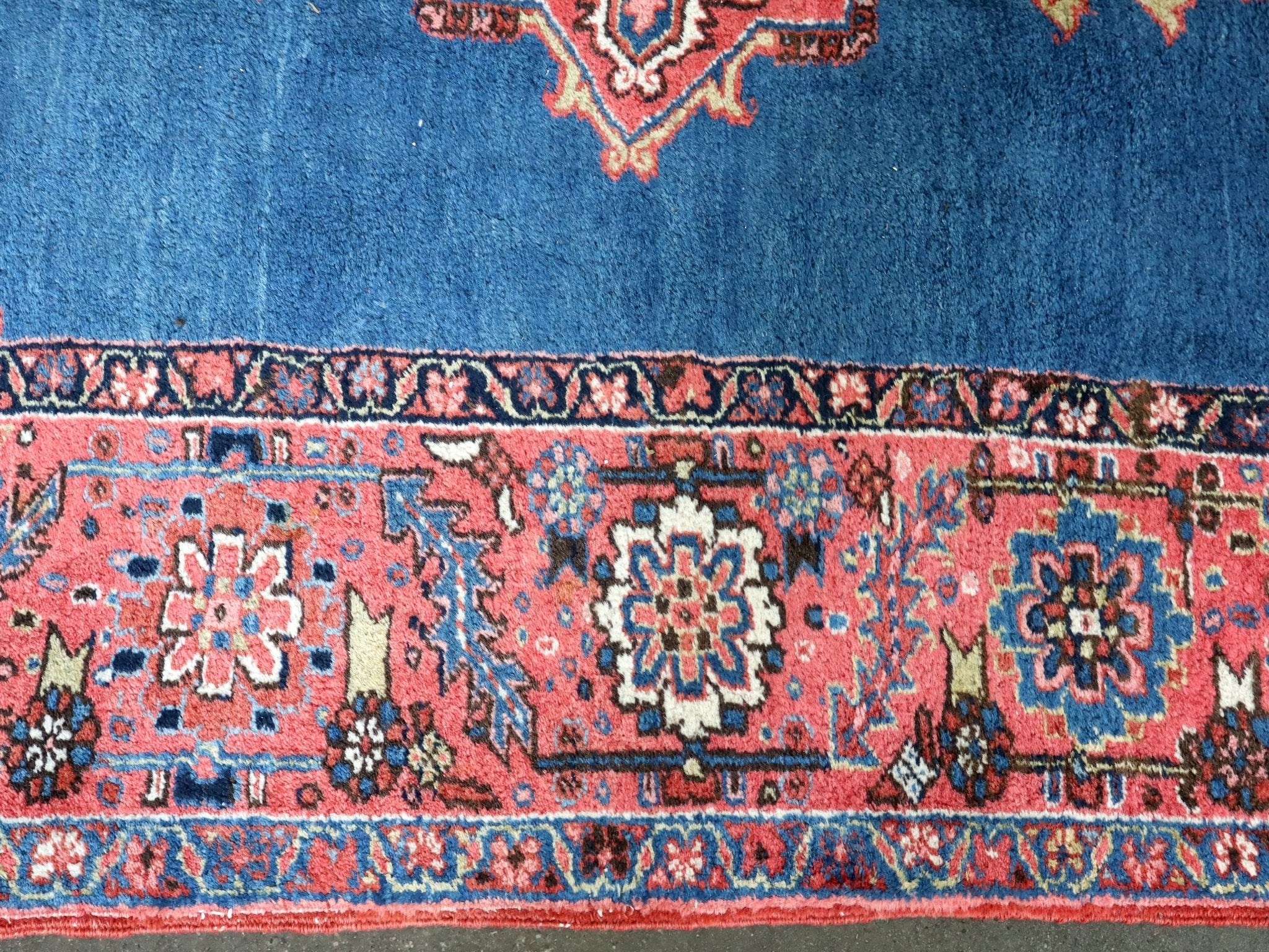 Persian Heriz rug border detail with red and cream medallions on blue background