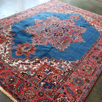 Persian Heriz rug laid at an angle, blue field with ornate red medallion center