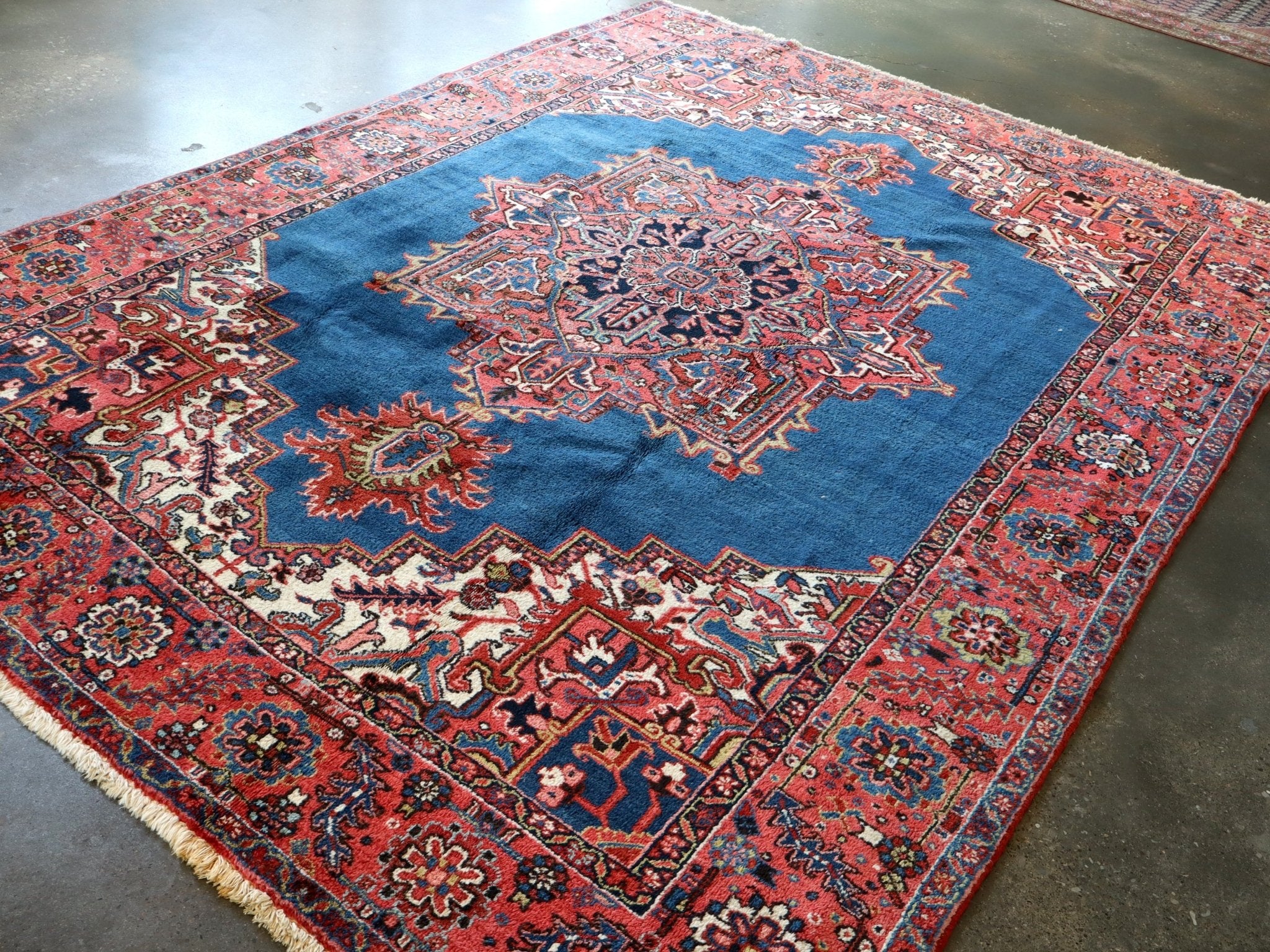 Persian Heriz rug laid at an angle, blue field with ornate red medallion center