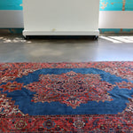 Heriz rug with blue center medallion and red patterned border, wide view