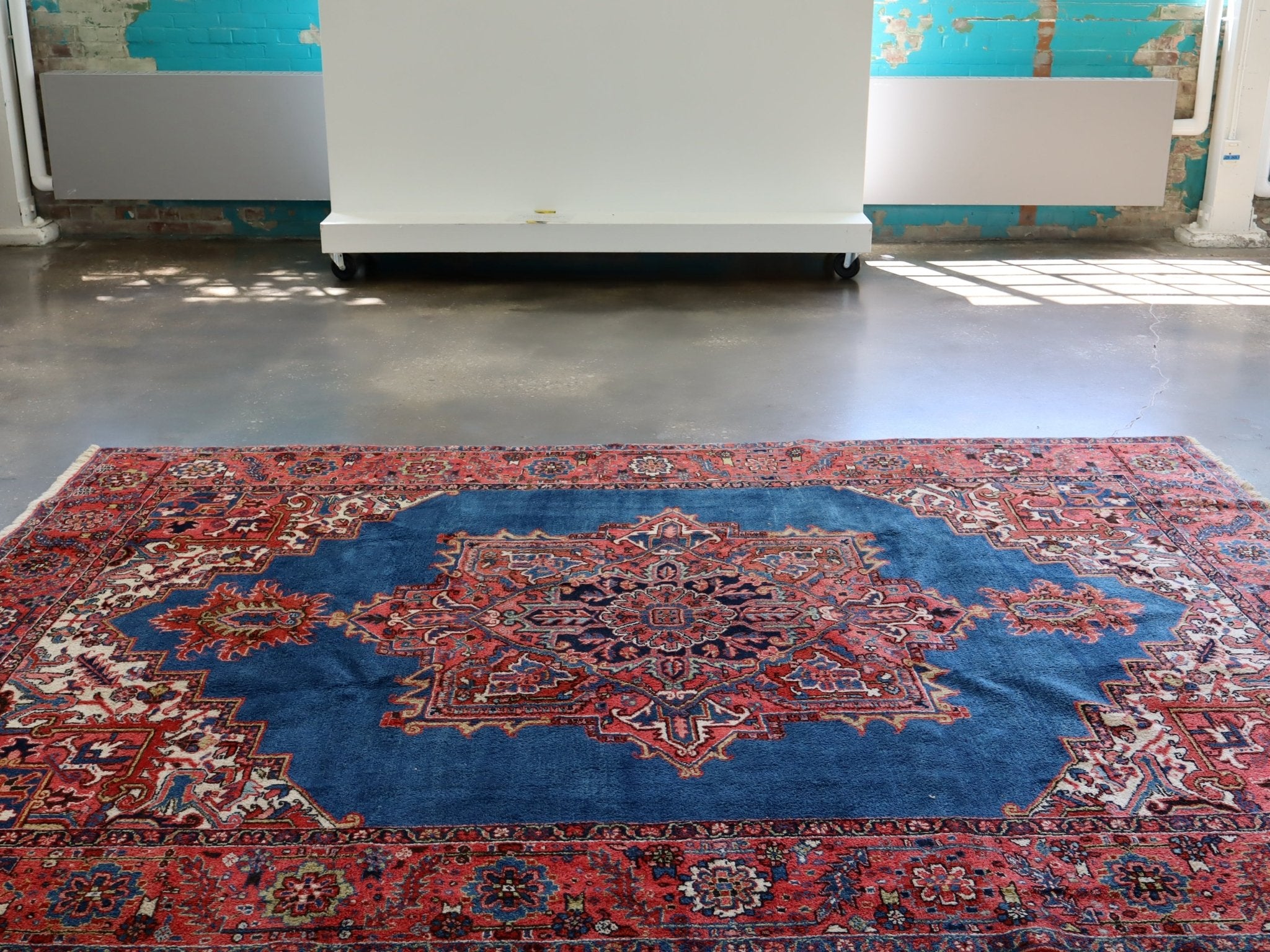 Heriz rug with blue center medallion and red patterned border, wide view