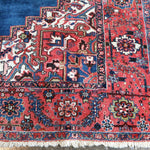 Persian Heriz rug corner detail with red field accents and intricate cream-and-blue pattern