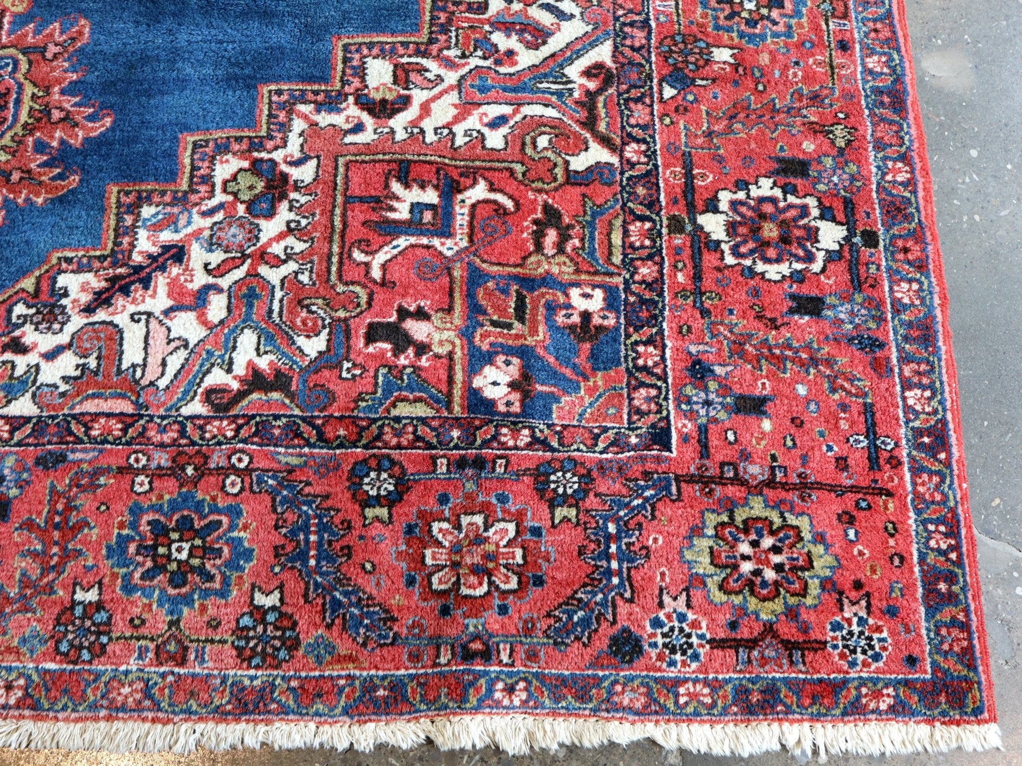 Persian Heriz rug corner detail with red field accents and intricate cream-and-blue pattern