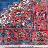 Persian Heriz rug corner detail with red field accents and intricate cream-and-blue pattern