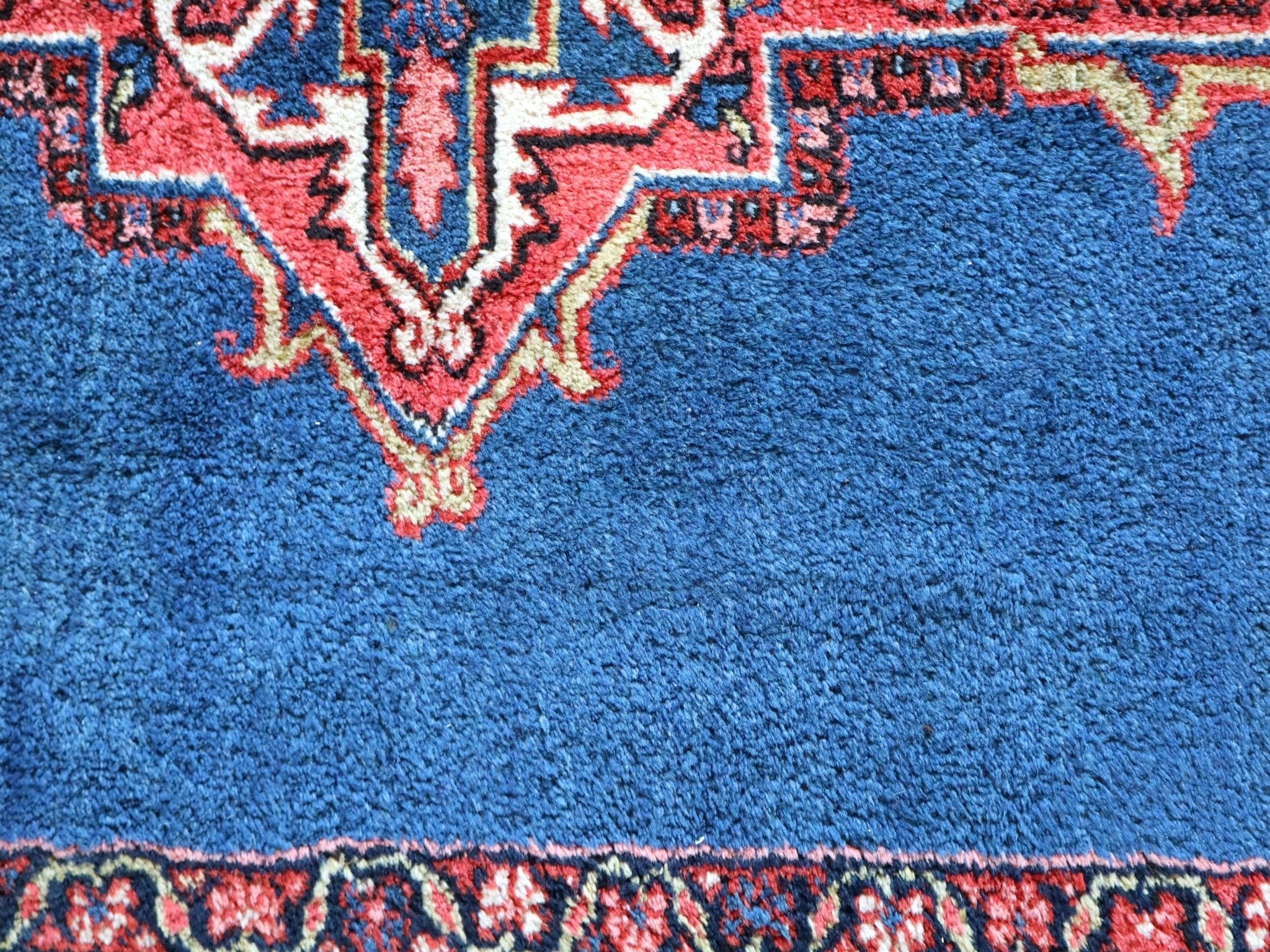 Heriz rug corner with blue field, red geometric medallion border, close-up