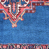 Heriz rug corner with blue field, red geometric medallion border, close-up