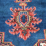 Heriz rug blue field with red rosette medallion and cream outlines, close-up