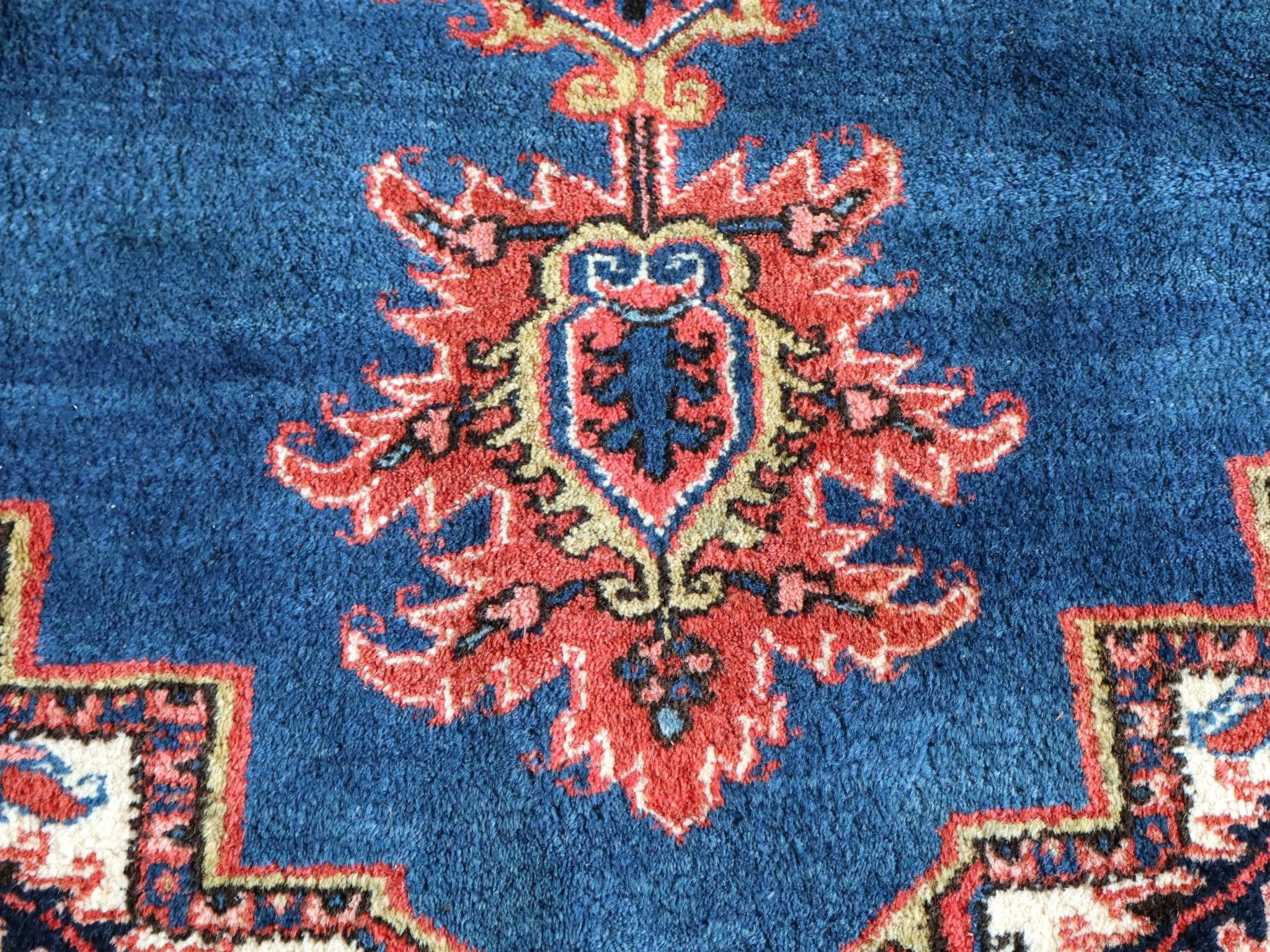 Heriz rug blue field with red rosette medallion and cream outlines, close-up