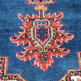 Heriz rug blue field with red rosette medallion and cream outlines, close-up