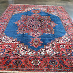 Persian Heriz rug featuring blue field, red border, and symmetrical central design