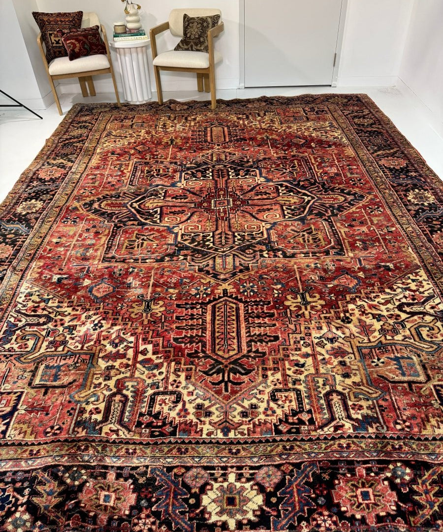 Persian Heriz rug on floor with red central medallion and detailed geometric borders