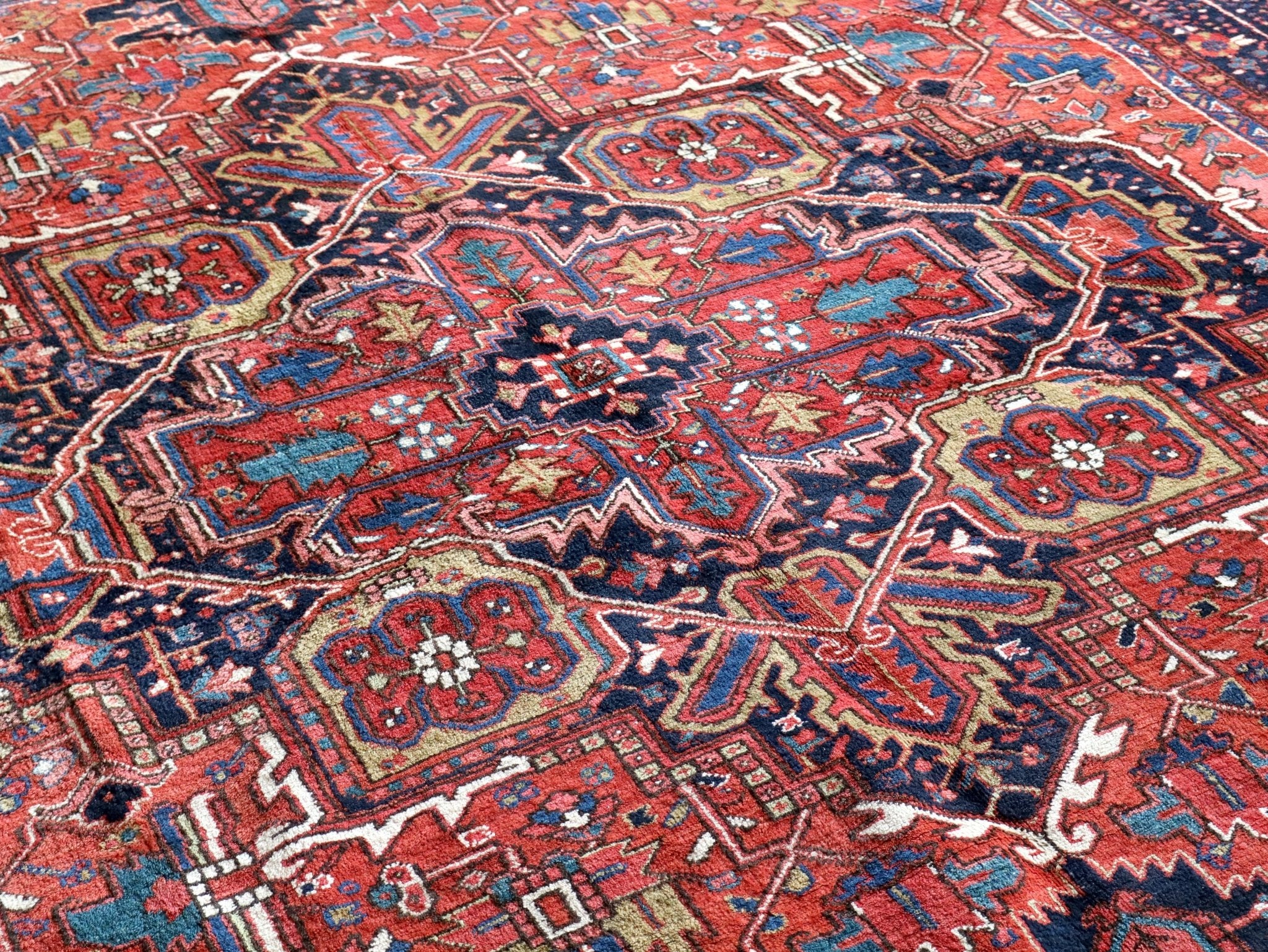 Persian Heriz rug surface with red, rust, navy, and turquoise repeating medallions