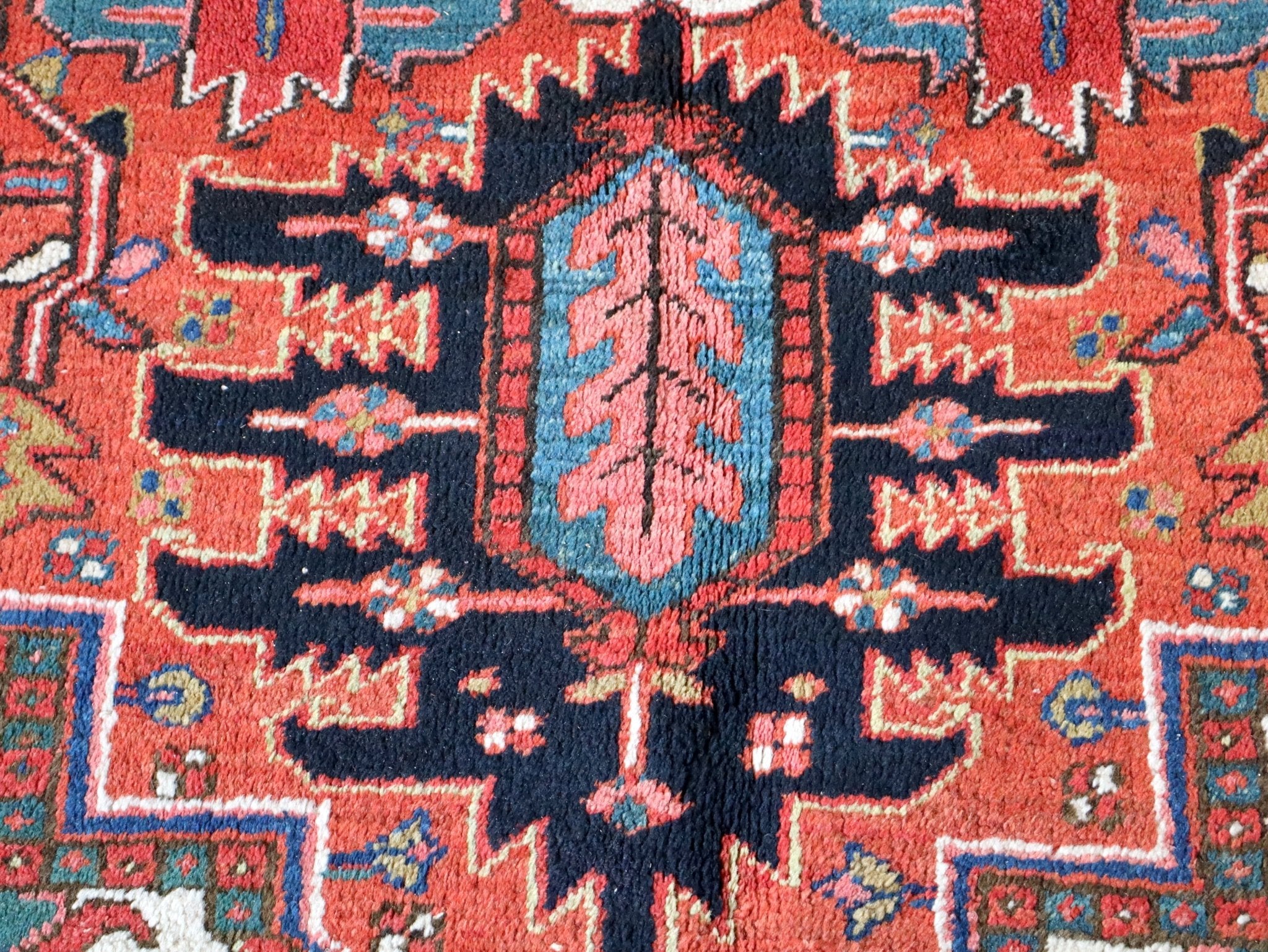 Heriz rug pattern close-up, red ground with dark navy cross and zigzag motif details