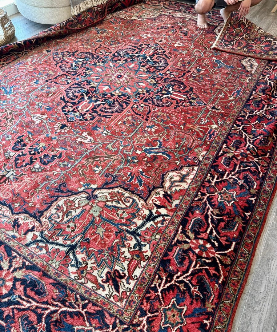Large Persian rug with red border, ornate medallion panel, and multicolor geometric patterning.