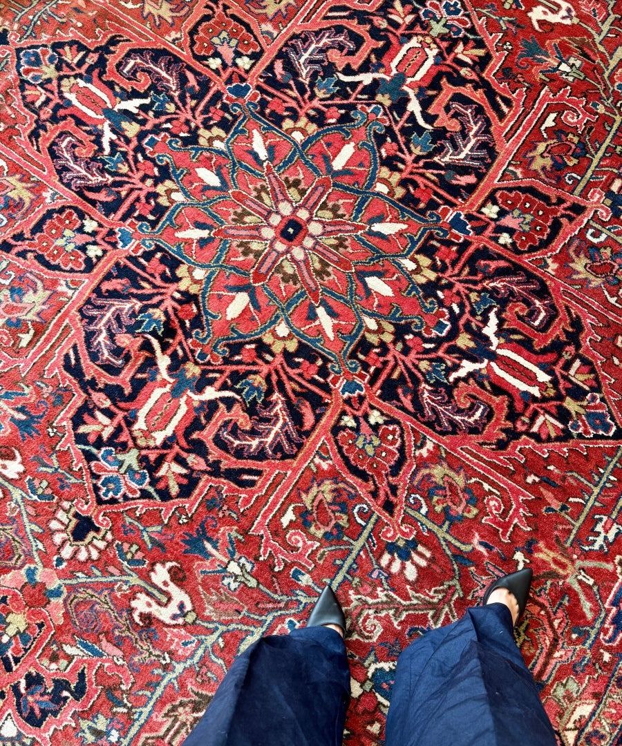 Heriz-style Persian rug with red field, central medallion, blue and cream floral motifs.