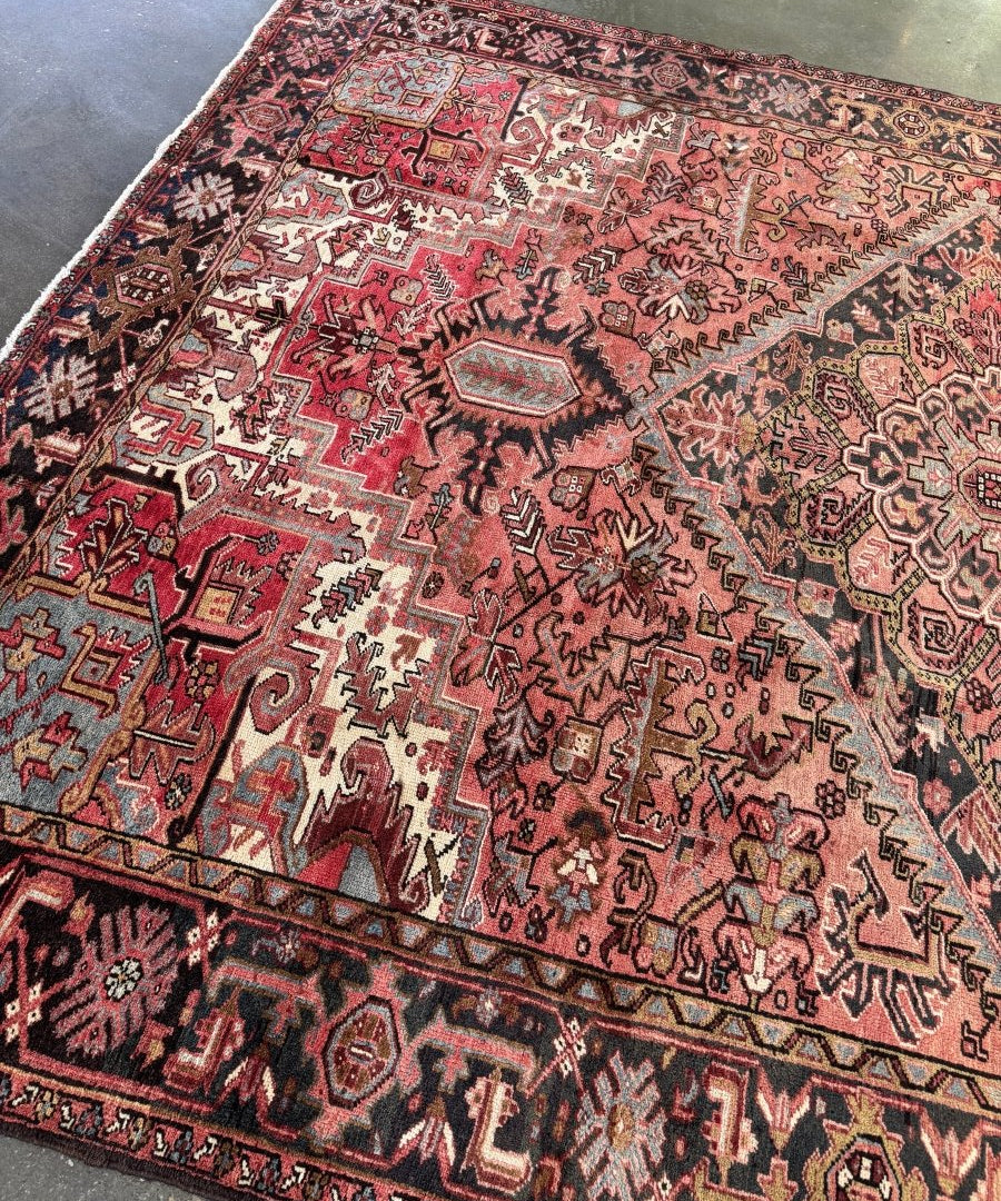 Persian Heriz rug corner view with red center, dark border, and cream accents