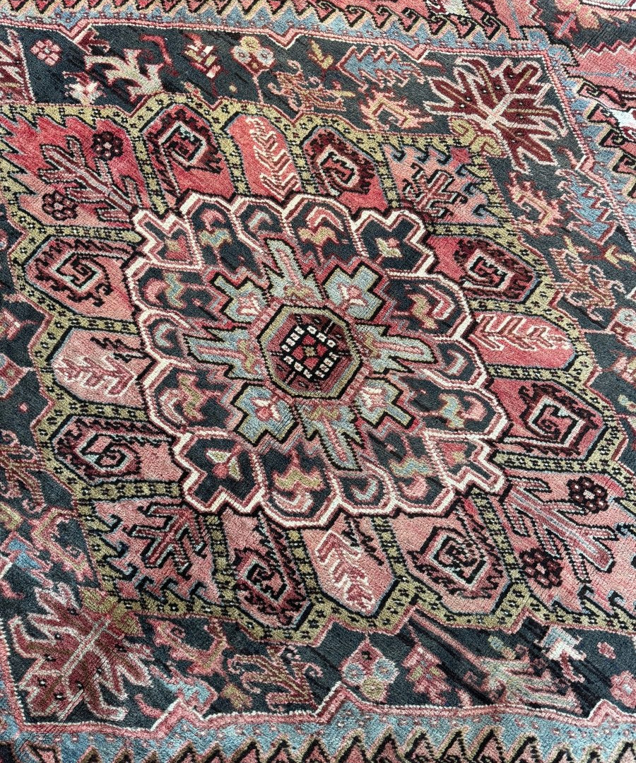 Close-up of Persian Heriz rug: red ground with navy, teal, and cream motifs