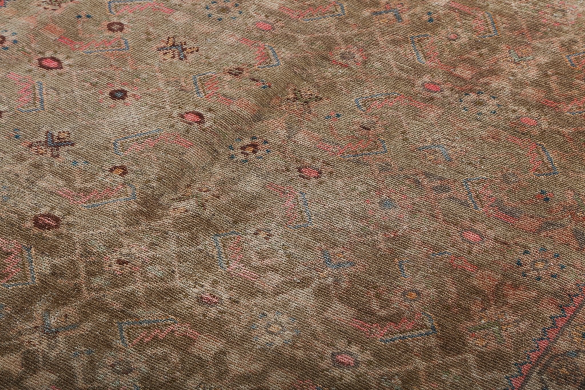 Close-up of beige Persian rug field with scattered red, blue, and teal motifs.