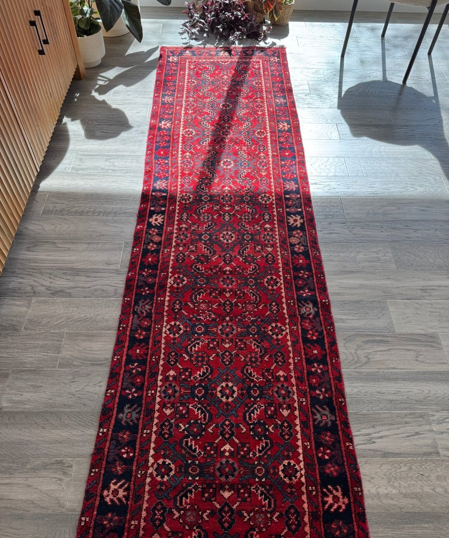 Red Persian-style runner rug with navy and beige medallion pattern and decorative border