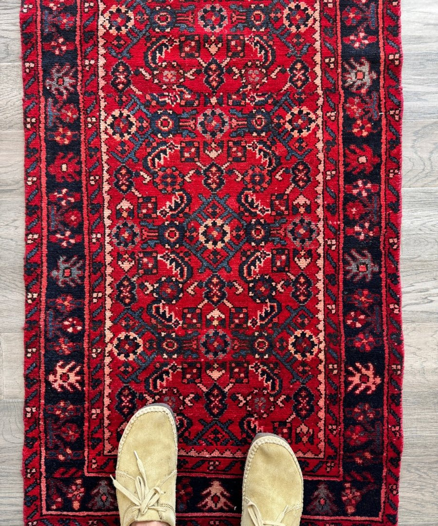 Persian-style runner rug with red field, navy and beige geometric motifs and border