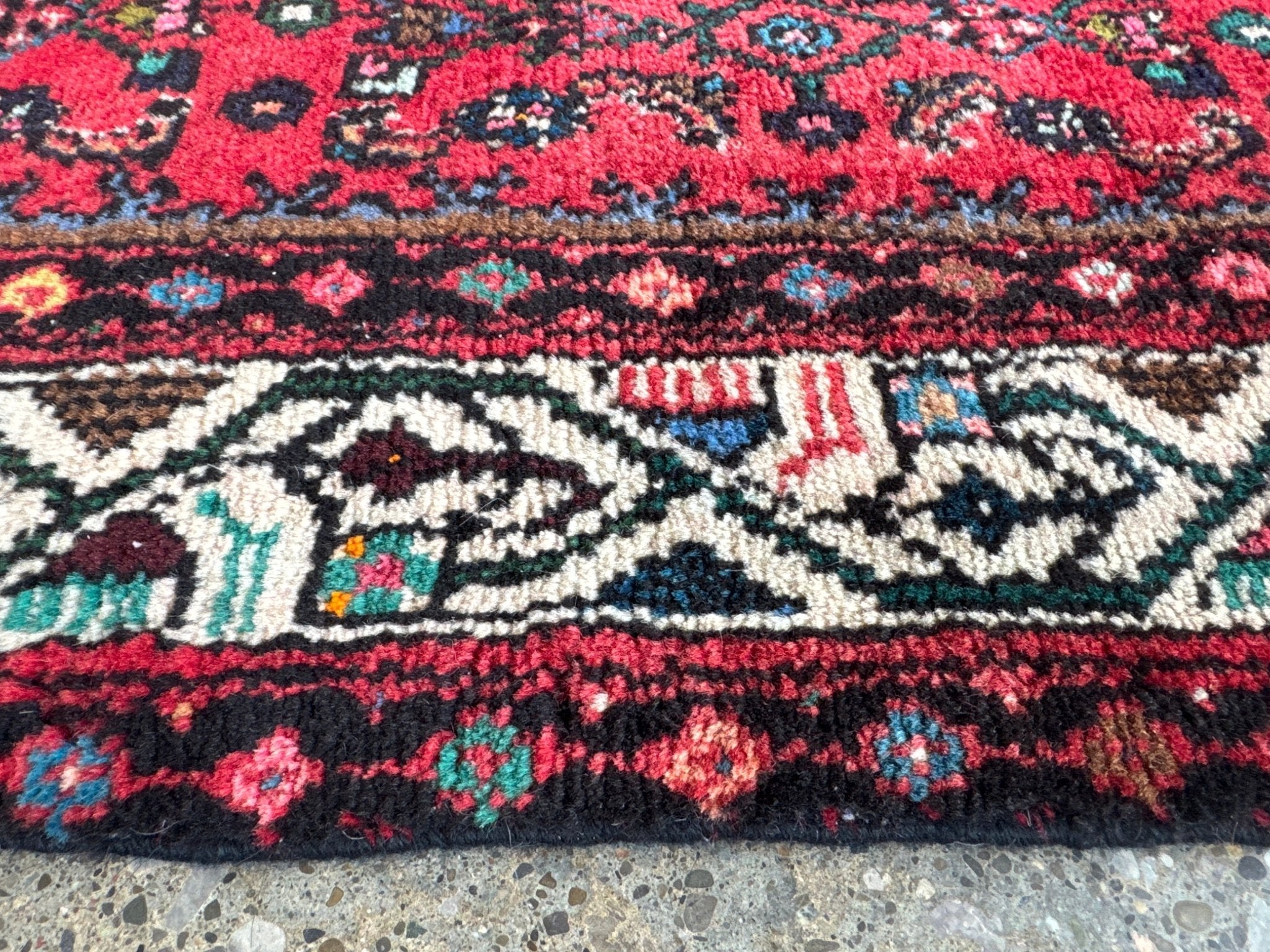 Lower section close-up of red runner rug with repeating medallion and stripe border.