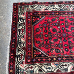 Persian runner rug, folded corner view with red center and cream border stripes