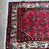 Persian runner rug, folded corner view with red center and cream border stripes