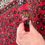 Close-up of red runner rug with dense floral and geometric pattern texture.