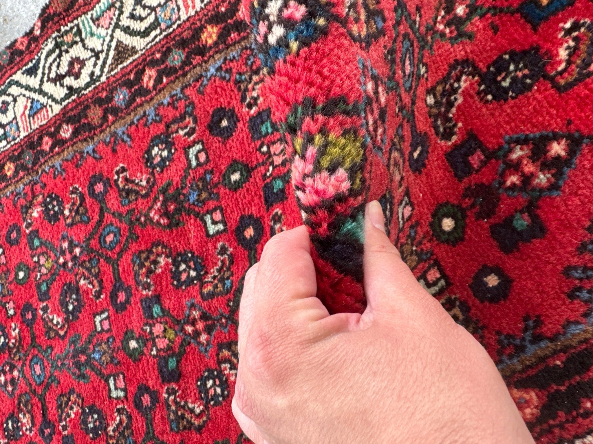 Close-up of red runner rug with dense floral and geometric pattern texture.
