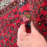 Close-up of red runner rug with dense floral and geometric pattern texture.