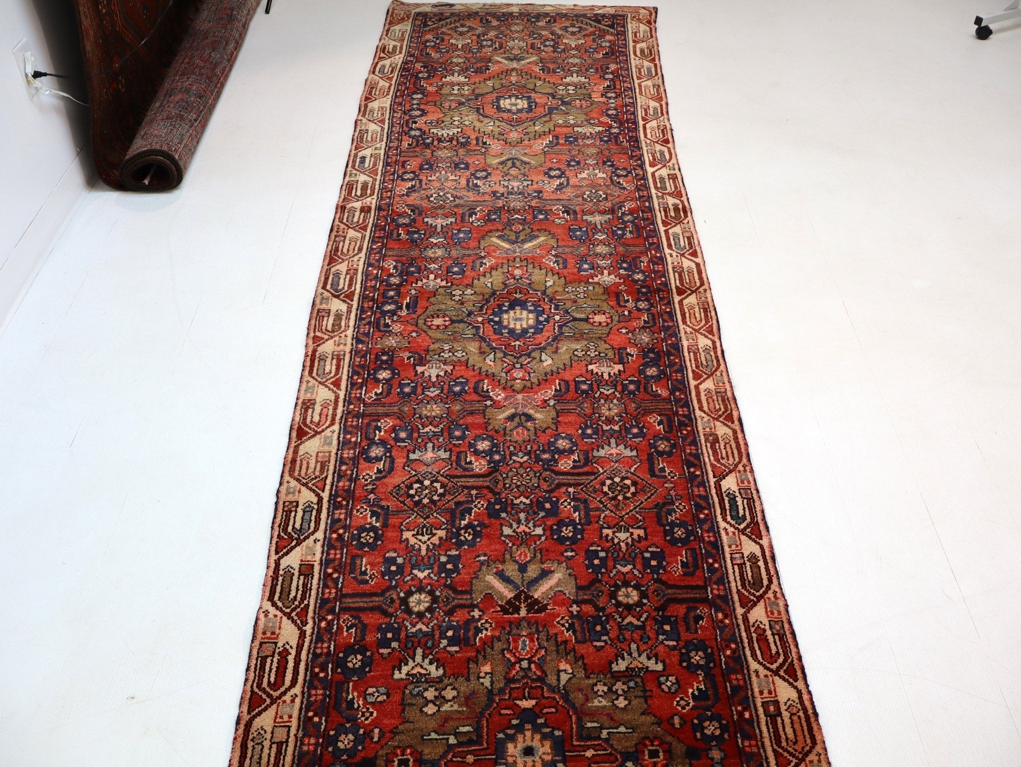 Runner rug viewed from above with dark red medallion and navy corner ornaments
