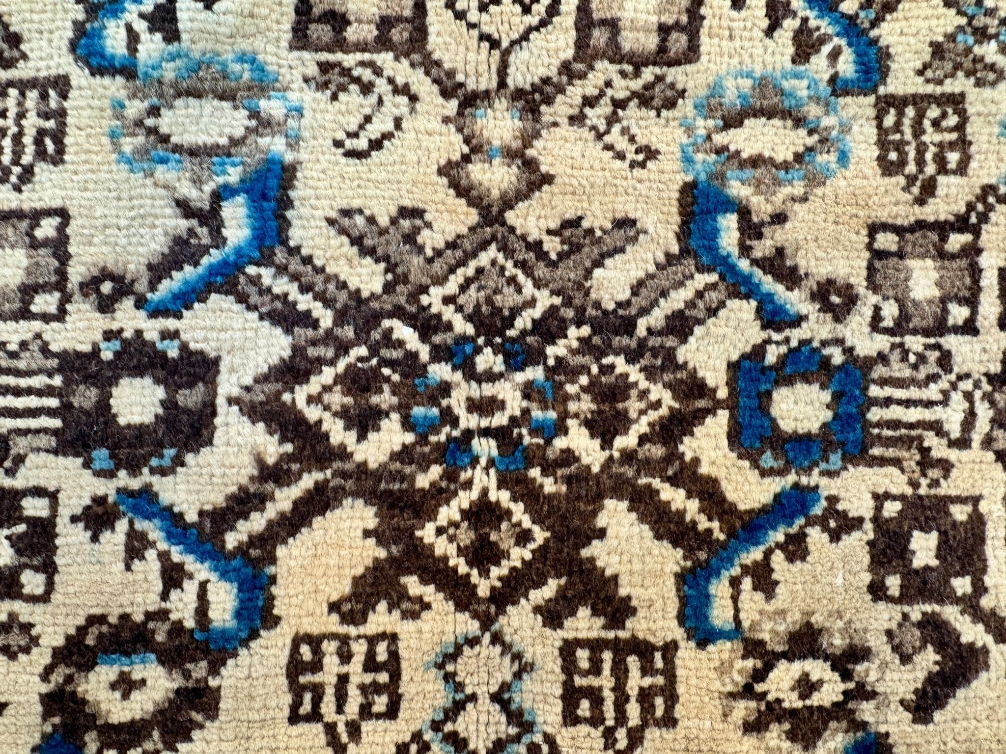 Persian runner rug weave detail with beige, dark brown, and vivid blue shapes