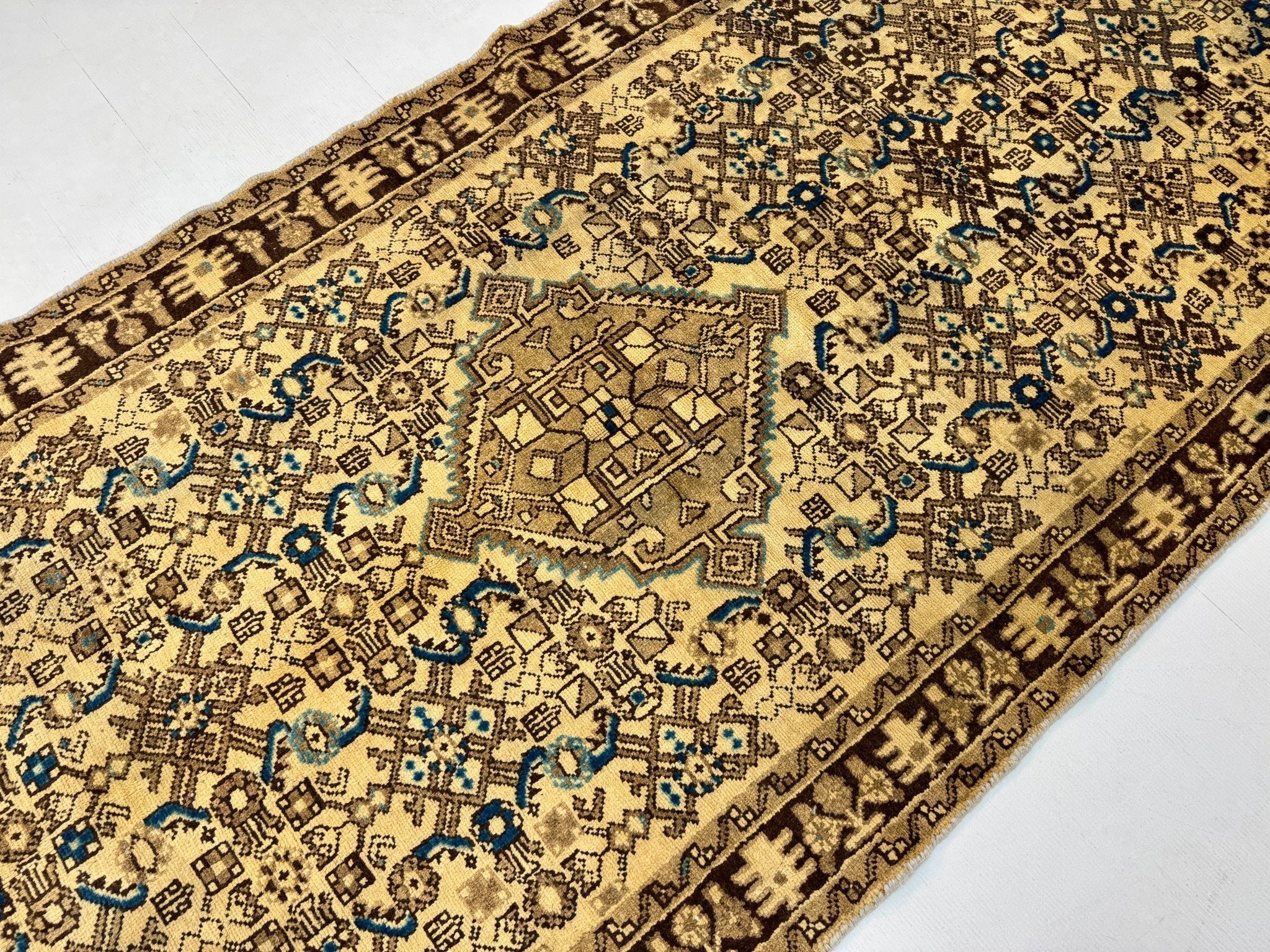 Persian runner rug corner detail with ornate beige pattern and blue accents