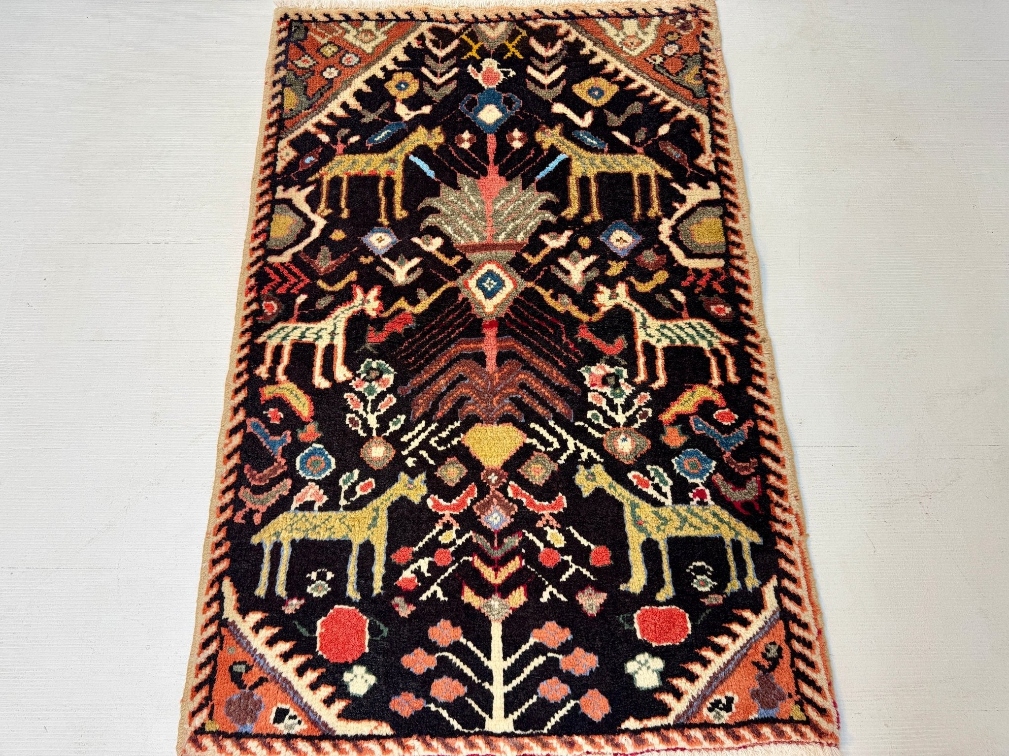 Persian Ilam-style rug with dark navy field, rust orange border, and multicolor medallion motifs