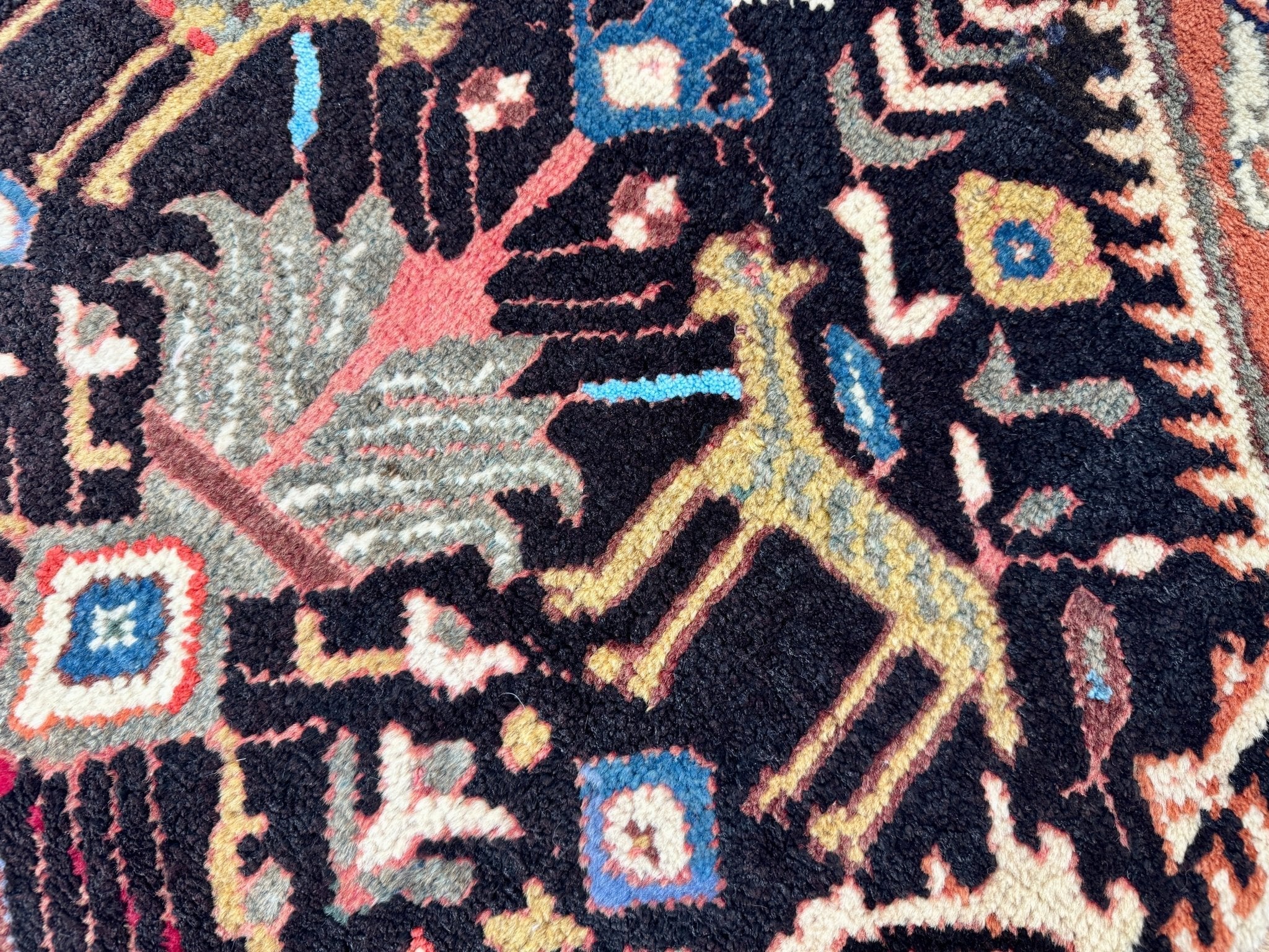 Close-up of Persian Ilam-style rug pattern on dark navy with red, blue, and cream accents