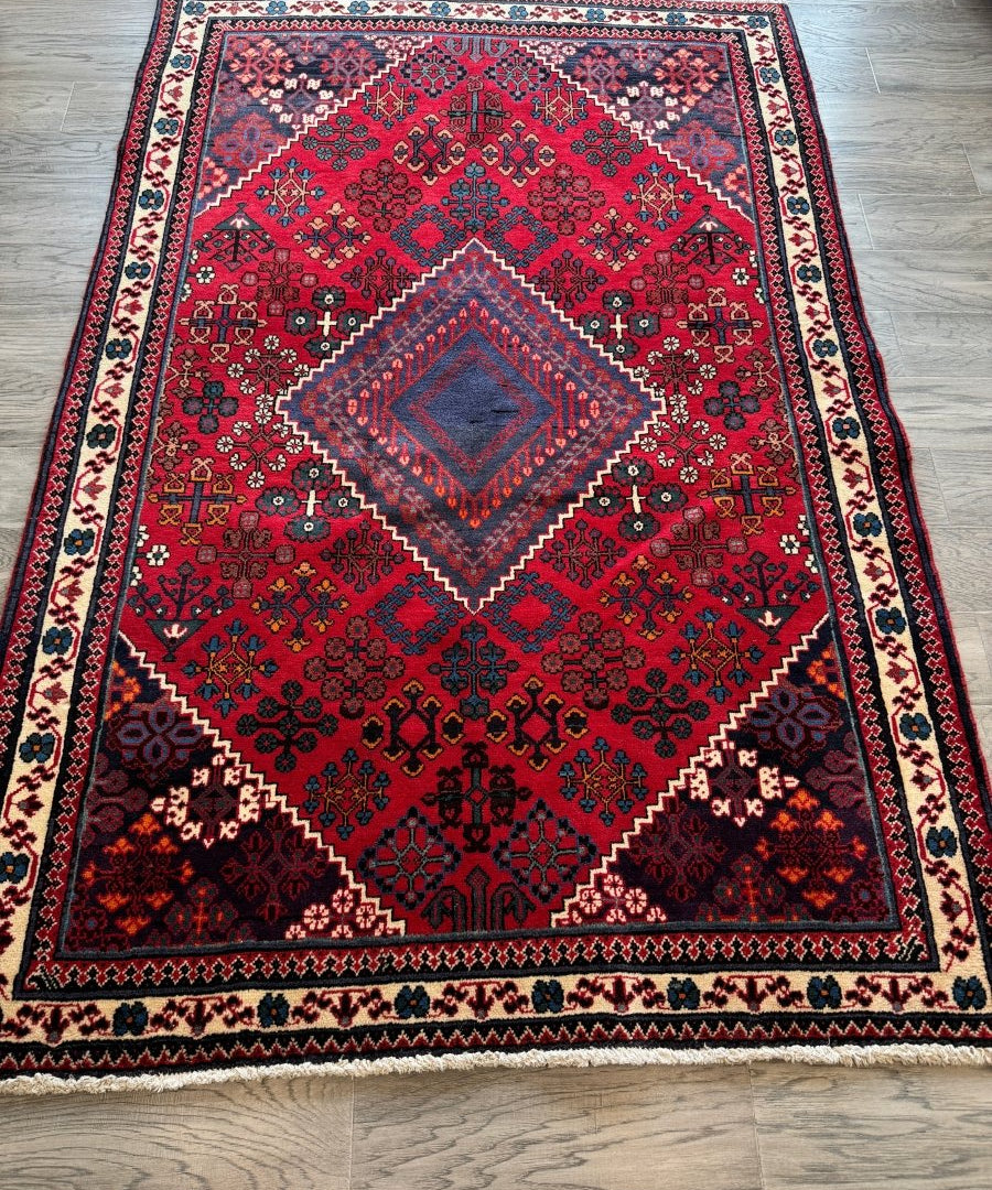 Persian Joshaqan rug, red field with diamond medallion and patterned border, wide view