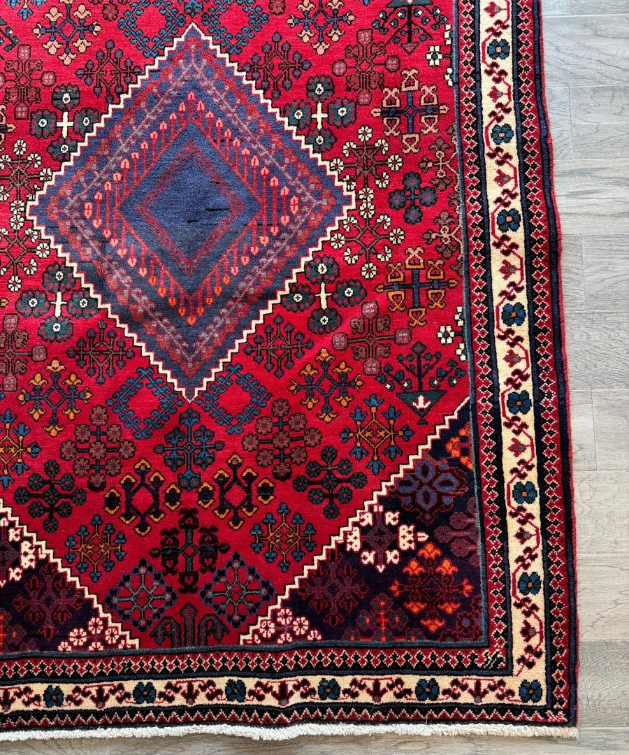 Persian Joshaqan rug corner detail with red and blue geometric motifs and border stripe