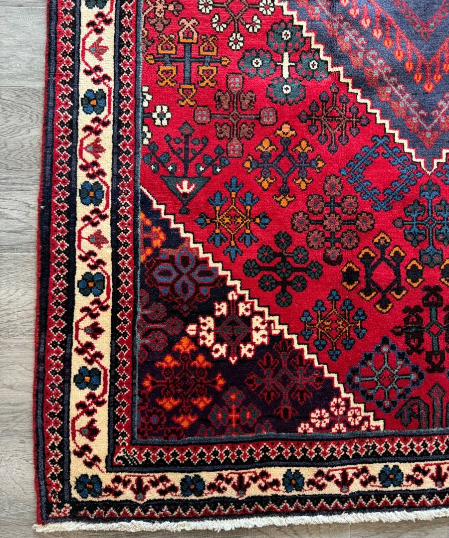 Persian Joshaqan rug section with red field, blue border, and multicolor floral geometry