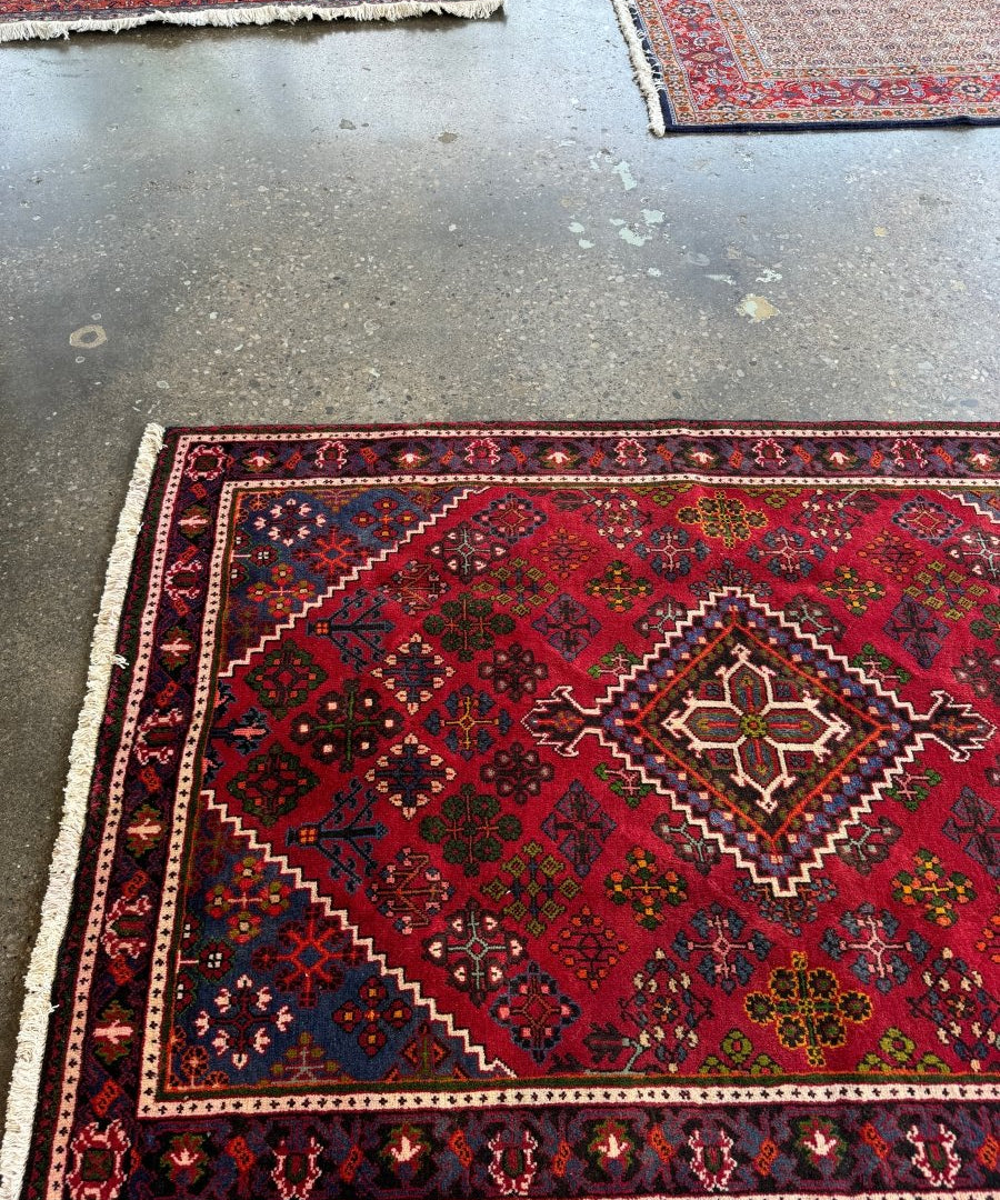 Red joshagan rug with large central diamond medallion and ornate geometric border