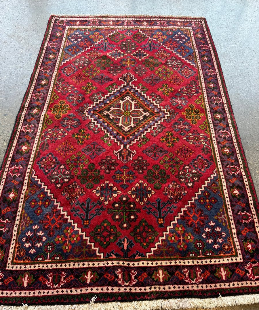 Persian-style joshagan rug with red field, diamond medallion, and multicolor border