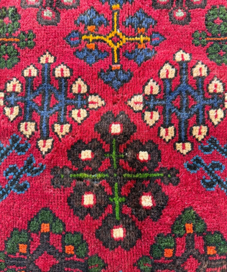 Close-up of red joshagan rug with blue floral motifs and green accents