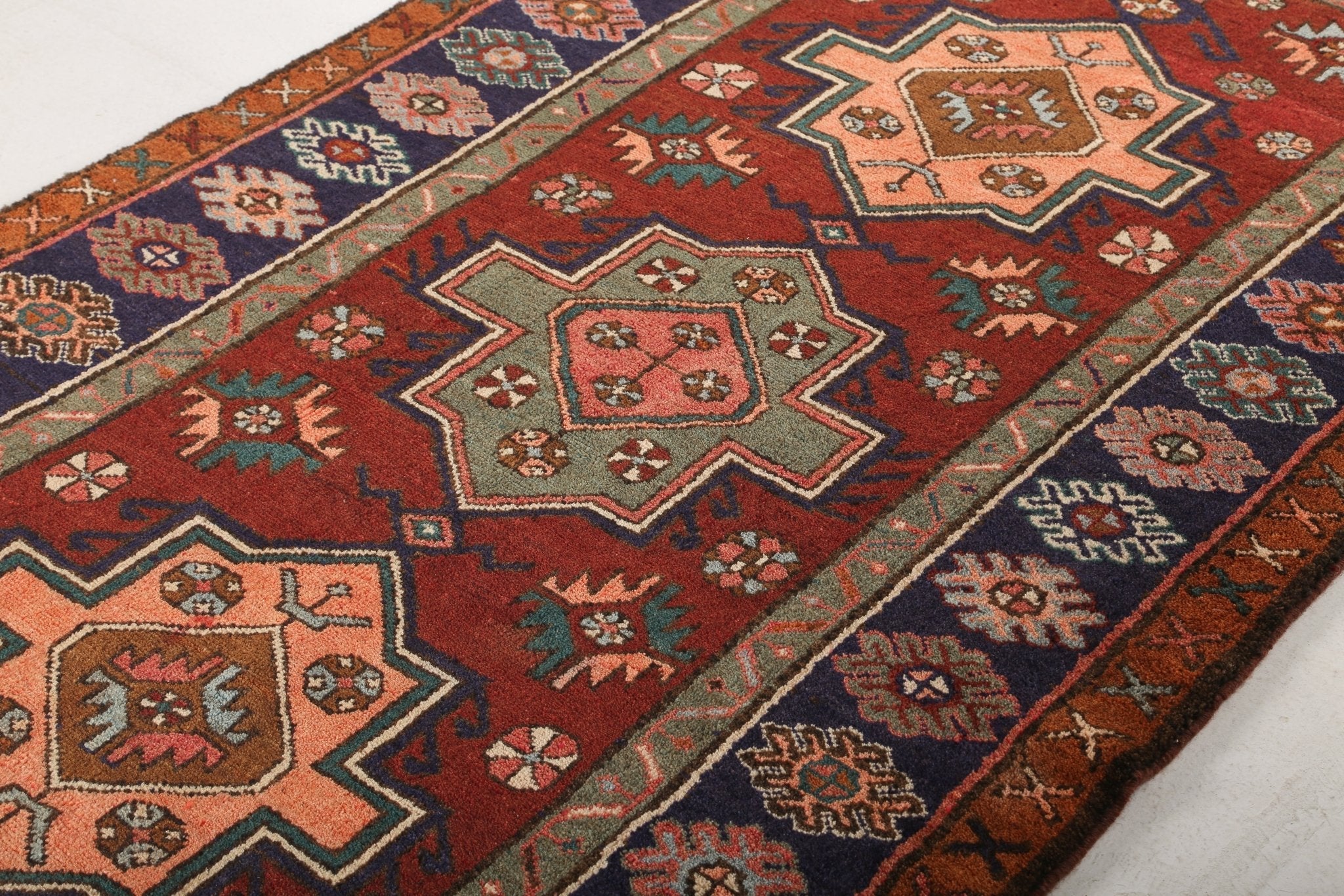 Persian Jozan rug angled view with red field and navy-green geometric pattern