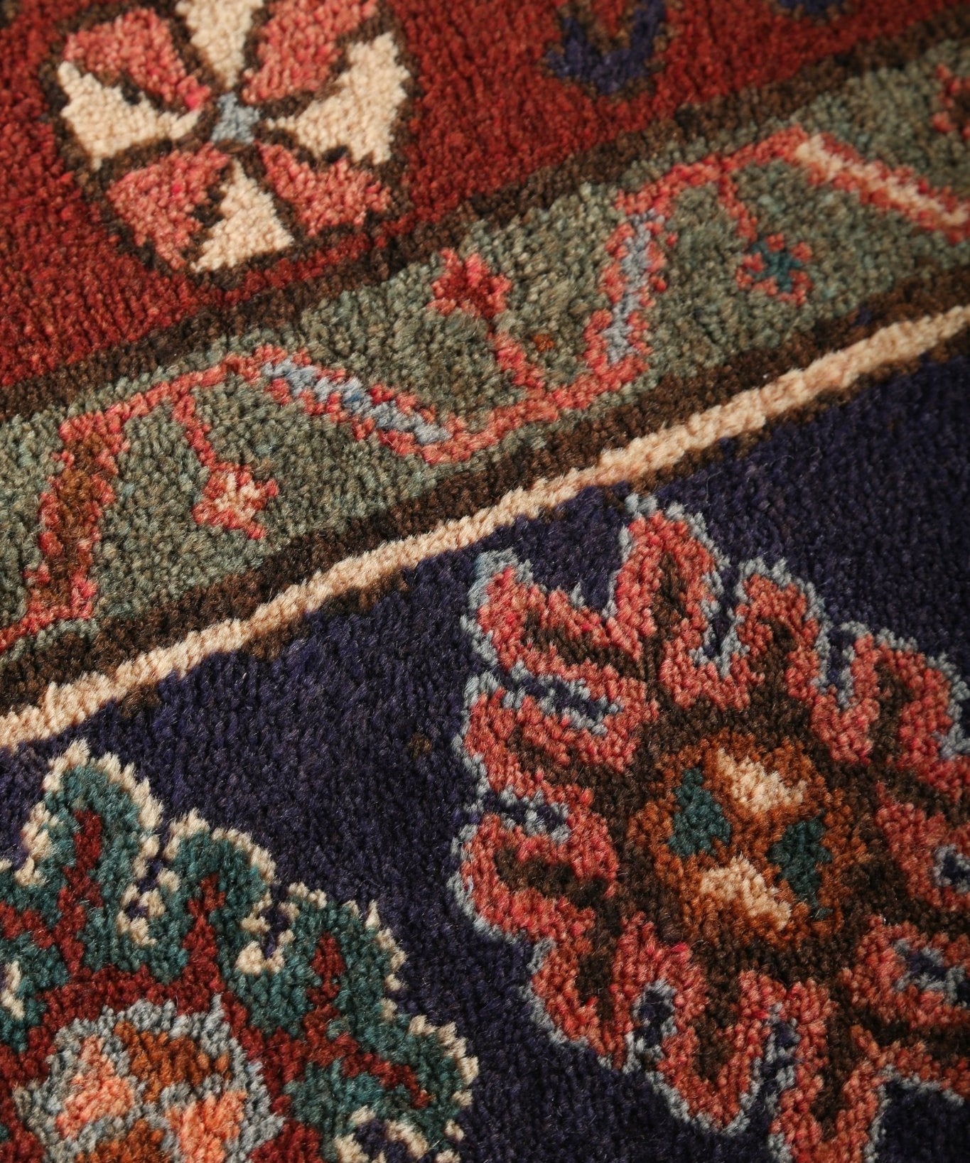 Persian Jozan rug close-up of textured pile with red, navy, and green motif shapes