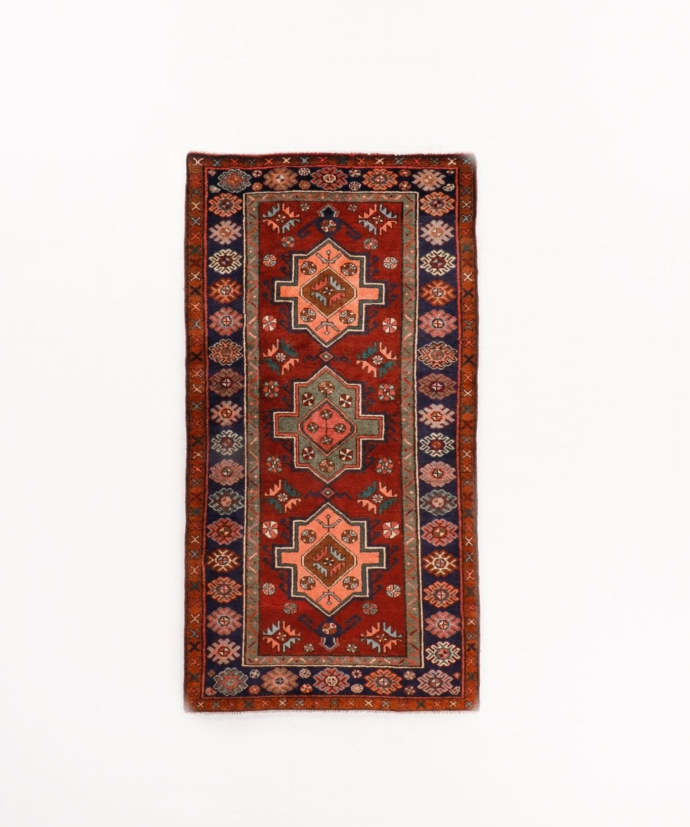 Rectangular area rug in red with navy border and three stacked diamond medallions.