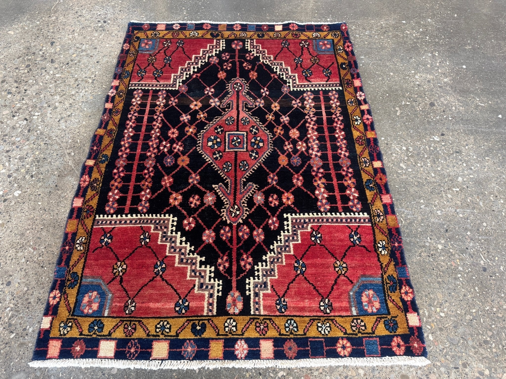 Geometric area rug with maroon field, navy lattice, and central medallion