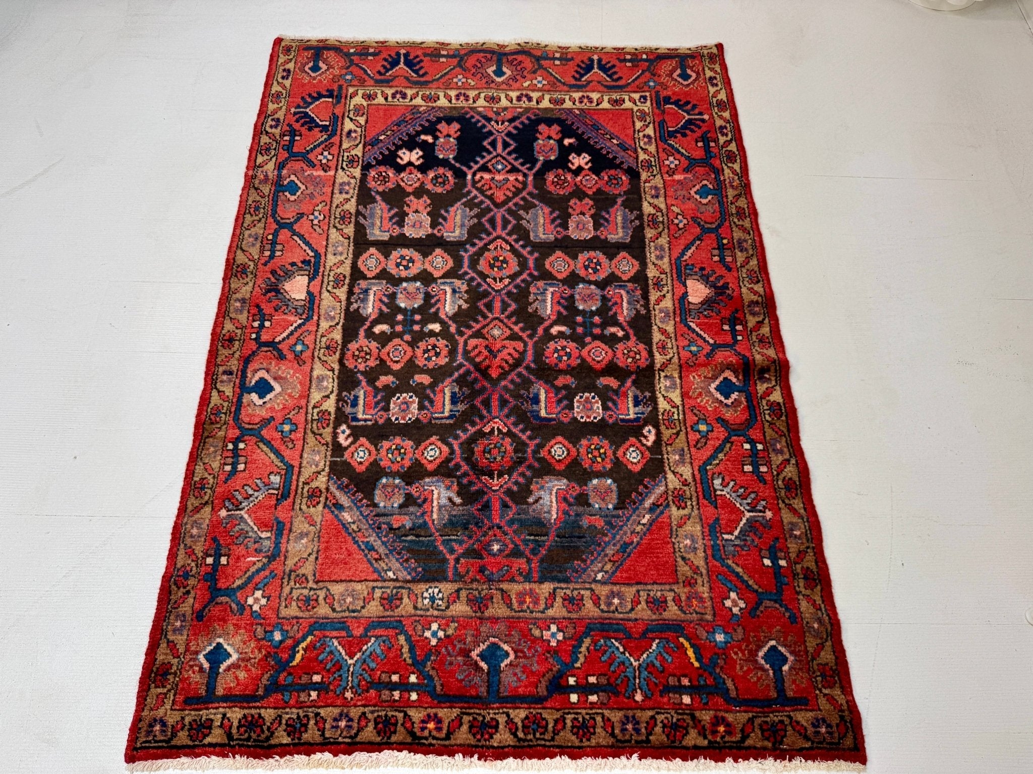 Rectangular Persian-style rug with red outer border and navy panel of tiny motifs