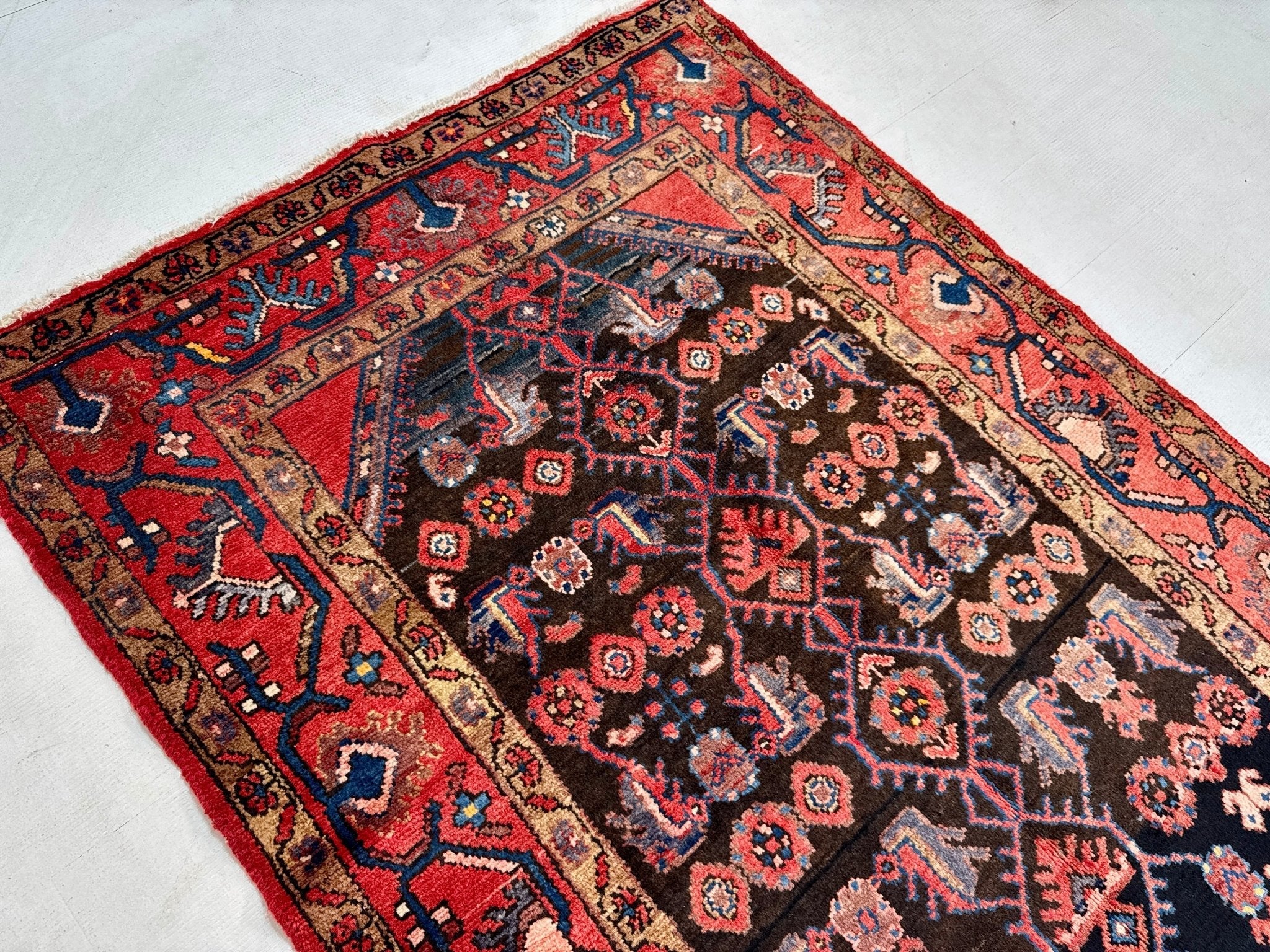 Persian-style area rug with dark navy field, red border, and repeating geometric motifs
