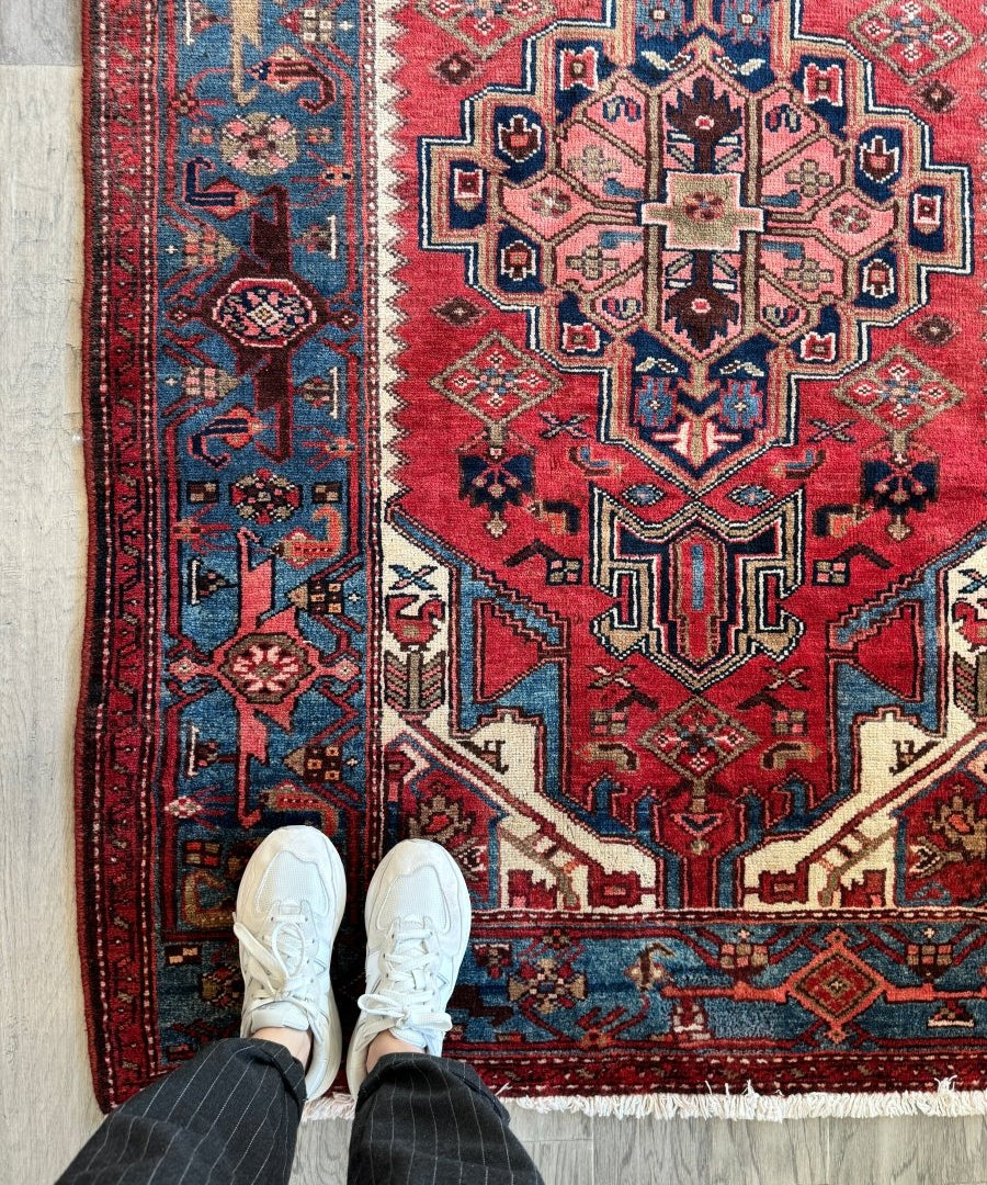Persian Jozan rug with red medallion, blue geometric border, and white fringe edges