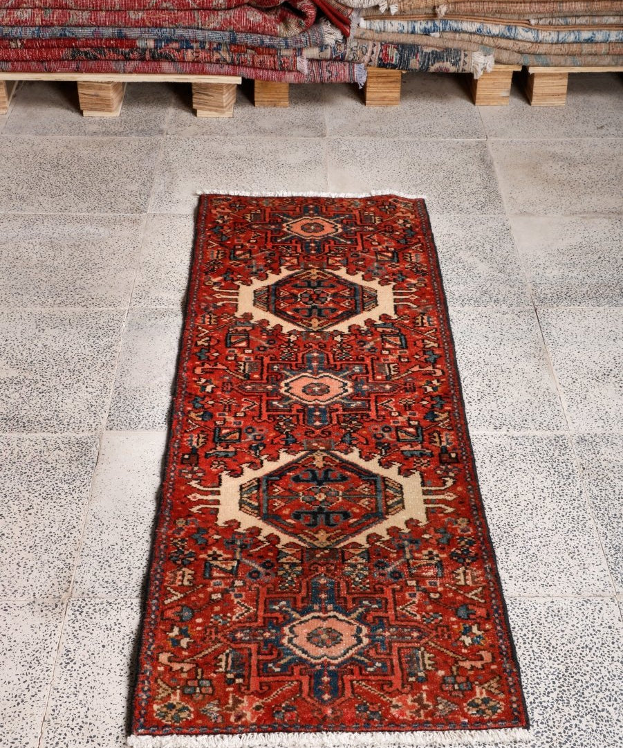 Geometric Persian-style runner rug in terracotta with navy and cream border