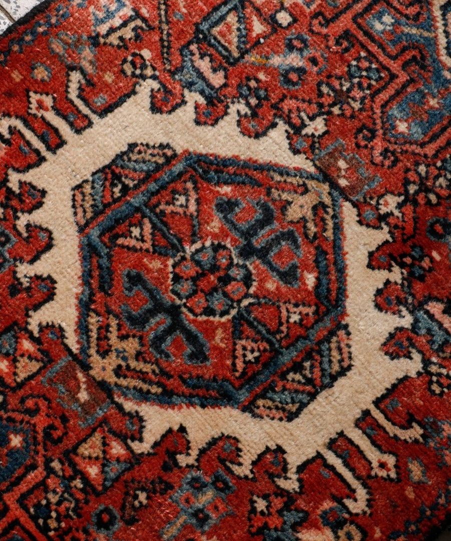 Close-up of Persian-style rug pattern with terracotta, navy, and cream motifs